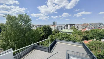 Geräumige Dachterrasse mit Holzboden und weitem Blick über die Stadt und umliegende Grünflächen.