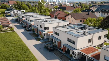 Luftaufnahme einer modernen Reihenhaussiedlung mit Flachdächern, Photovoltaikanlagen und grünen Dächern.