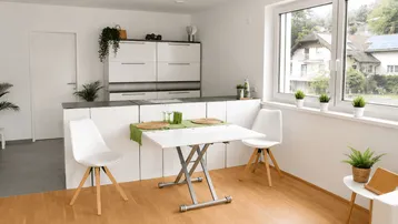 Moderne Küche mit weißen Schränken, Essbereich und großem Fenster mit Ausblick.