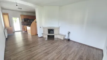 Geräumiger Wohnbereich mit Kamin und offenem Übergang zur Küche, ausgestattet mit Laminatboden.