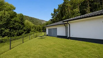 Ansicht des Bungalows mit Garten und Blick auf die bewaldeten Hügel in der Ferne.