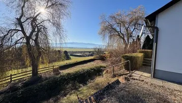 Gartenbereich mit Bäumen und Hecken, der einen weiten Blick auf die Landschaft bietet.