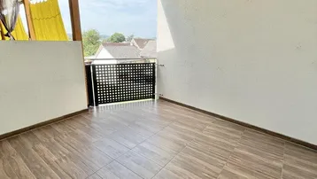Geräumiger Balkon mit Fliesenboden und Blick auf die umliegende Nachbarschaft und grüne Umgebung.