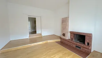 Gemütliches Wohnzimmer mit traditionellem Kamin und Kachelofen, aufgeteilt in zwei Ebenen.