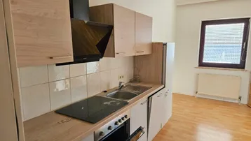 Funktionale Einbauküche mit hellen Holzfronten, integrierten Geräten und Fensterblick.