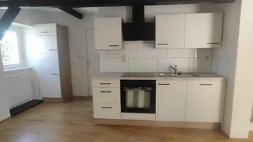 Moderne Einbauküche mit weißen Schränken, Kochfeld und Spüle in einem hellen Raum.