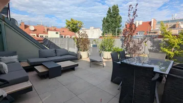 Weitläufige Dachterrasse mit Essbereich, Lounge-Möbeln und Panoramablick auf die Stadt.