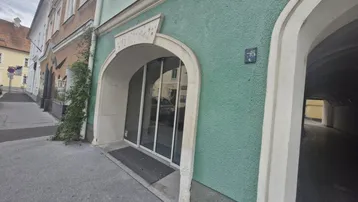 Historisches Gebäude mit grün gestrichener Fassade und einem gewölbten Eingangsbereich zur Straße hin.