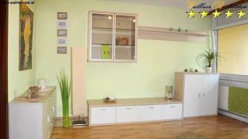 Helles Wohnzimmer mit hellgrünen Wänden, Holzfußboden und modernen Möbeln.