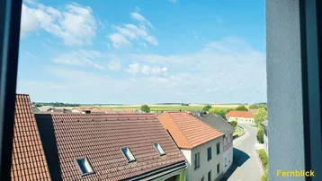 Weitblick aus dem Fenster über Dächer und die umliegende ländliche Landschaft.
