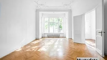 Heller Raum mit Fischgrätparkett, Stuckdecke und großen Fenstern, ideal als Wohnzimmer.