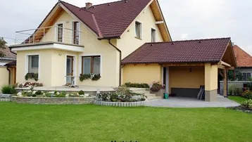 Modernes Einfamilienhaus mit Satteldach, Carport, Terrasse und gepflegtem Garten mit Rasenfläche.