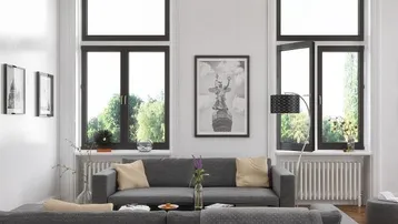 Helles Wohnzimmer mit modernem grauem Sofa, hohen Fenstern und Blick ins Grüne.