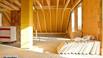 Unfertiger Dachboden im Rohbau mit sichtbaren Holzbalken und Baumaterialien, bereit für den Ausbau.