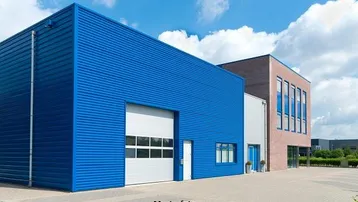 Modernes Gewerbegebäude mit blauer Fassade und großem Rolltor unter blauem Himmel.