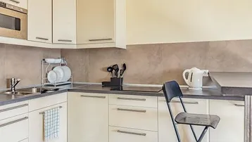 Helle Einbauküche mit cremefarbenen Schränken, integriertem Backofen und moderner Arbeitsplatte.