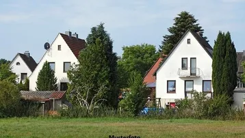 Weiße Einfamilienhäuser mit Satteldächern, umgeben von viel Grün und einem Feld im Vordergrund.