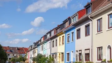 Reihenhauszeile mit farbenfrohen Fassaden und Satteldächern unter blauem Himmel