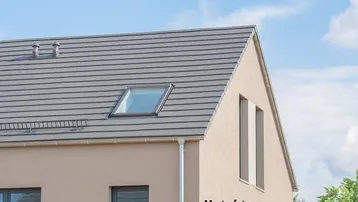 Dach eines modernen Hauses mit Dachfenster und beiger Fassade unter blauem Himmel.