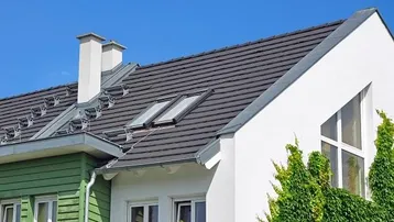 Modernes Einfamilienhaus mit Satteldach, Dachfenstern und einer Kombination aus weißer und grüner Fassade.