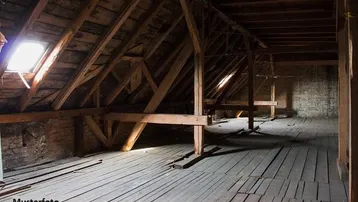 Geräumiger Dachboden mit sichtbaren Holzbalken und Dachfenstern, bereit für den Ausbau.