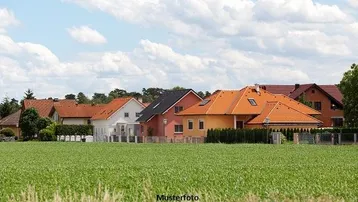 Reihen von Einfamilienhäusern mit verschiedenen Dachformen und einem weiten Feld im Vordergrund unter blauem Himmel.