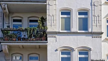 Detailansicht einer weißen Altbaufassade mit einem verzierten Balkon voller Pflanzen und großen Fenstern.