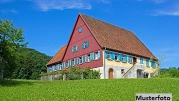 Traditionelles Landhaus mit roter Fassade und blauen Fensterläden, eingebettet in eine grüne Hügellandschaft unter blauem Himmel.