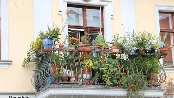 Ein blumenreicher Balkon an einer hellgelben Fassade mit schmiedeeisernem Geländer und traditionellen Fenstern.