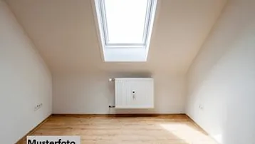 Heller Dachraum mit Schrägdecken, Dachfenster und Holzfußboden, ideal für ein Schlafzimmer oder Büro.