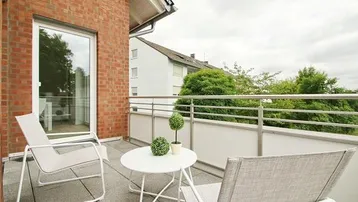 Heller Balkon mit modernen Gartenmöbeln und Blick ins Grüne, ideal zum Entspannen.