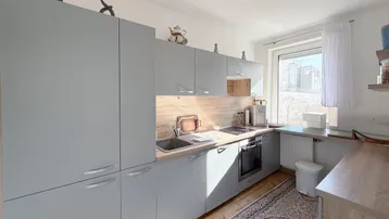 Moderne Küche mit grauen Schränken, Holzarbeitsplatten und integrierten Geräten.