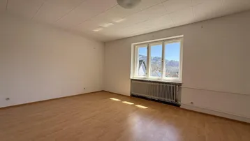 Helles Schlafzimmer mit Laminatboden und weitem Blick auf die umliegenden Berge.