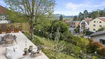 Großzügige Terrasse mit Essbereich und Lounge-Möbeln, umgeben von viel Grün und Fernblick.