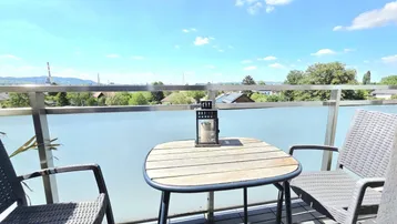 Heller Balkon mit Sitzgelegenheiten und weitem Blick über die Umgebung unter blauem Himmel.