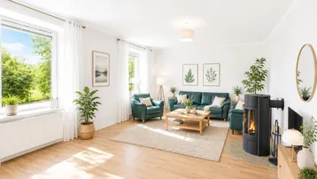 Helles Wohnzimmer mit Holzboden, Kaminofen und Blick ins Grüne durch große Fenster.