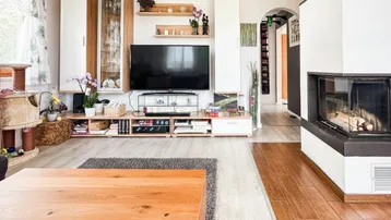 Gemütliches Wohnzimmer mit Kamin, modernem TV-Möbel und hellem Laminatboden.
