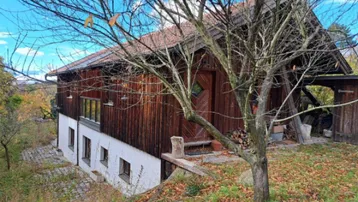 Rustikales Holzhaus mit traditioneller Architektur und umgebender Natur im Herbst.