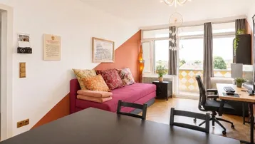 Helles Wohn- und Esszimmer mit Parkettboden, gemütlichem Sofa und Zugang zum Balkon.