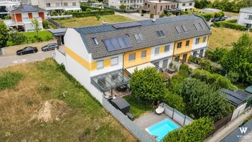Luftaufnahme eines Reihenhauses mit Garten, Terrasse, Pool und Solaranlage auf dem Dach.