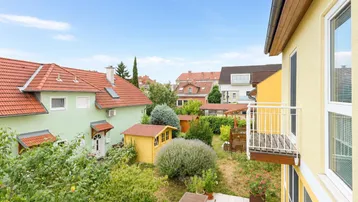 Blick über den Garten mit Gartenhäuschen und einem kleinen Balkon am Haus.