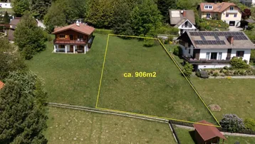 Luftaufnahme eines grünen Grundstücks von ca. 906 m² umgeben von Wohnhäusern und Bäumen.