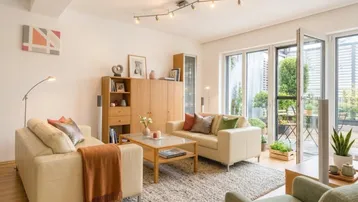 Helles Wohnzimmer mit beigen Sofas, Holzboden und direktem Zugang zu einer Außenterrasse.