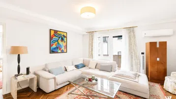 Helles Wohnzimmer mit bequemem Sofa, Parkettboden und Zugang zu einem Balkon, ausgestattet mit Klimaanlage.