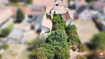 Luftaufnahme eines Wohnhauses mit großem Garten und umliegender grüner Landschaft.