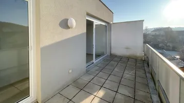 Geräumiger Balkon mit Fliesenboden und Blick auf die Umgebung unter strahlendem Sonnenschein.