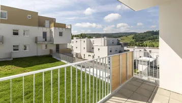 Heller Balkon mit Blick auf die umliegende Wohnsiedlung und grüne Hügellandschaft.