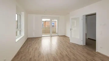 Helles, leeres Wohnzimmer mit Laminatboden und Zugang zu einem Balkon, bereit für die individuelle Gestaltung.