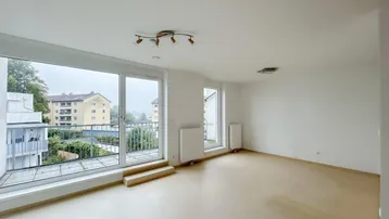 Helles, leeres Zimmer mit großen Fenstern und Zugang zu einem Balkon, bereit zur individuellen Gestaltung.