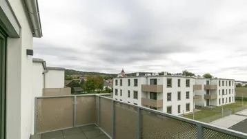 Blick vom Balkon auf die umliegenden Neubauten und die weite Landschaft unter bewölktem Himmel.
